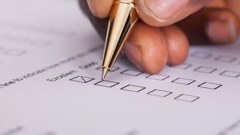 A hand marking a checkbox on a form with a pen.