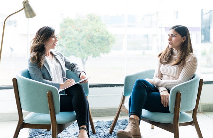 Two women seated and engaged in a counselling session.