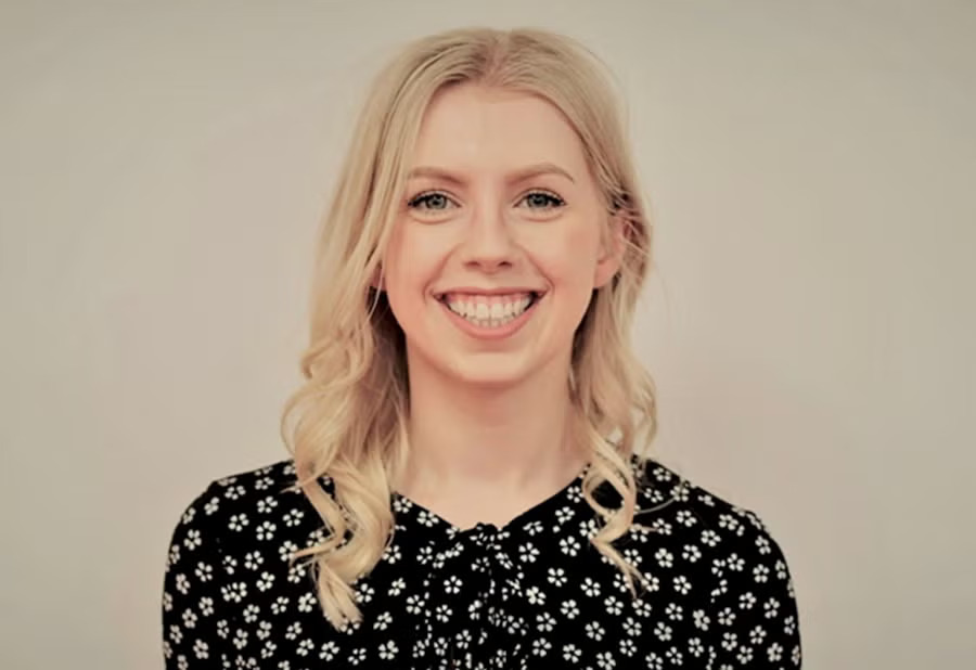 A woman smiling at the camera with a gray background.