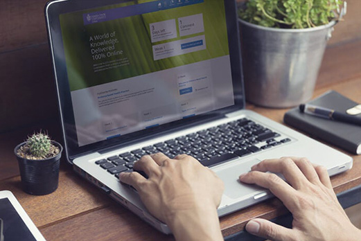 Person using a laptop at a wooden desk, accessing James Cook University’s online learning platform.